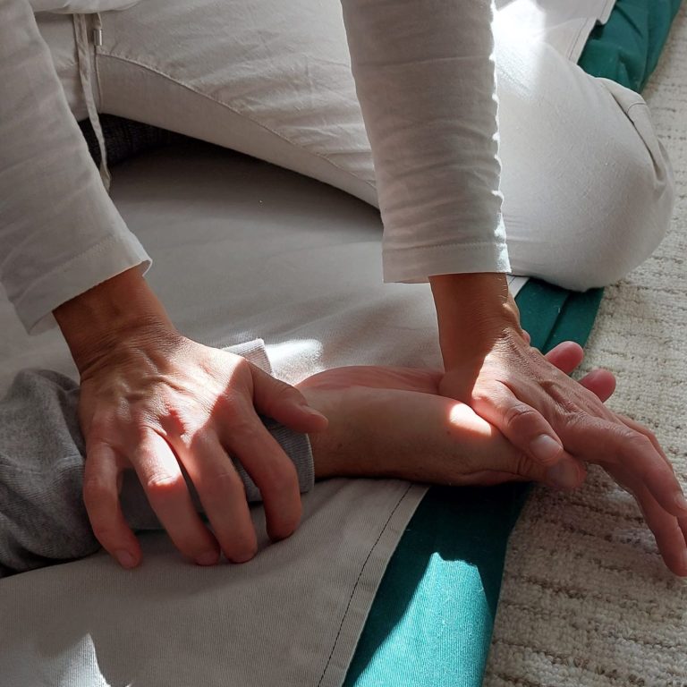 Eine Person führt eine Massage oder Behandlung an einem Unterarm durch.