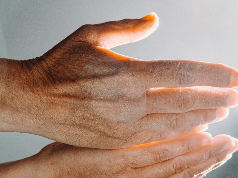 Eine Hand massiert die Fußsohle einer Person, entspannende Atmosphäre.